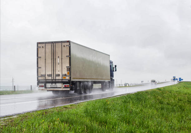 A trucker on a truck with a semitrailer transports cargo in poor visibility on the road, rain. Highway traffic in bad weather. Copy space for text A trucker on a truck with a semitrailer transports cargo in poor visibility on the road, rain. Highway traffic in bad weather. Copy space for text, danger truck rain stock pictures, royalty-free photos & images
