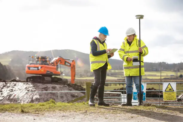 A survey crew using a rover with a smart antenna that uses visual positioning to map points on a construction site. They are working in the North East of England on a green field site and are talking while also using a digital tablet.