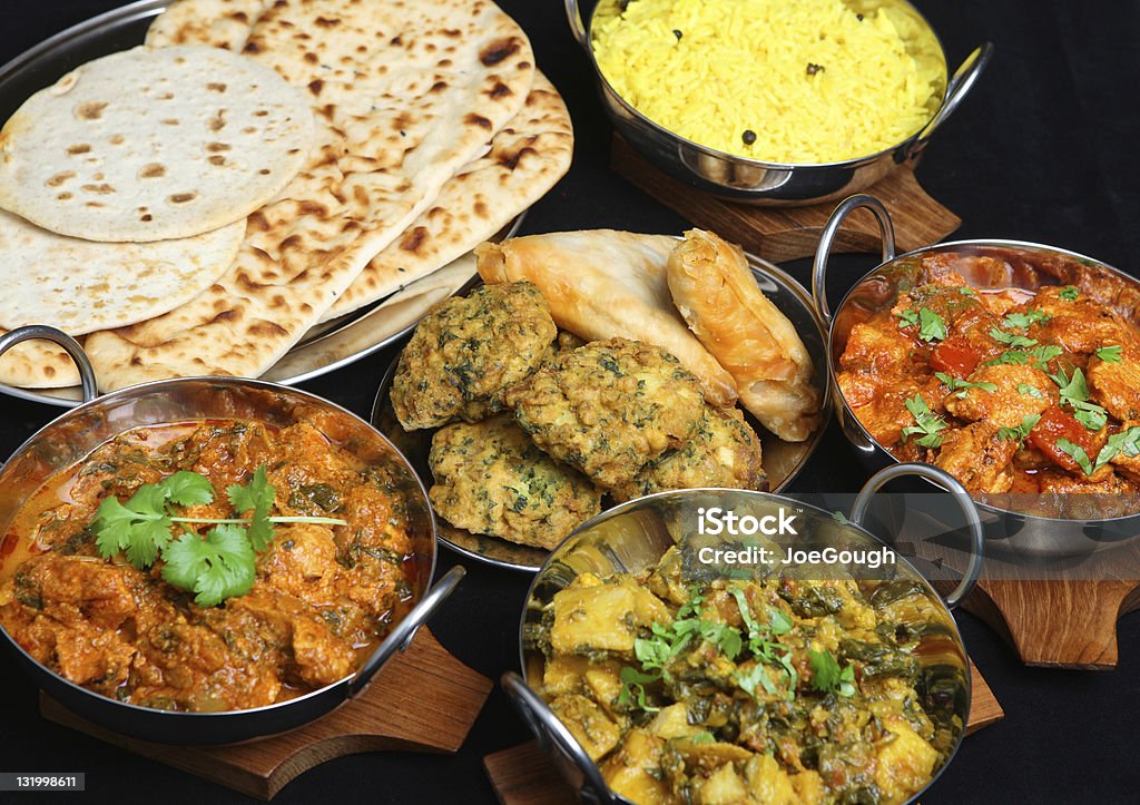 Photo of plates of different types of Indian food Indian food with curries, rice, naan bread, samosas and pakora. Indian Food Stock Photo