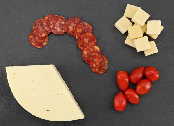 fette di salame piccante con cubetti di parmigiano, formaggio morbido e pomodorini su un piatto da portata - provolone foto e immagini stock