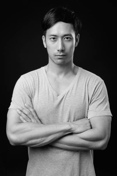 istock Young handsome Asian man against black background 1319988112