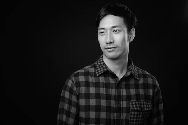 istock Young handsome Asian man against black background 1319988127