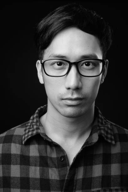Young handsome Asian man against black background