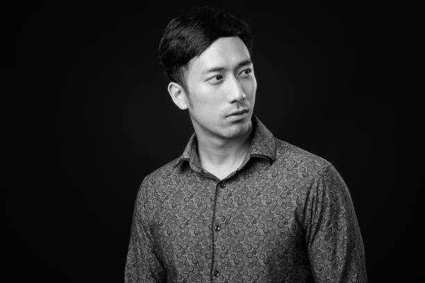 istock Young handsome Asian businessman against black background 1319988136