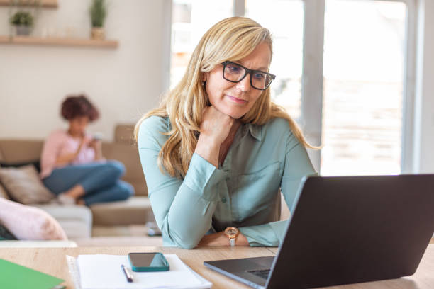 istock Mature woman using laptop while sitting at the kitchen table 1319988138