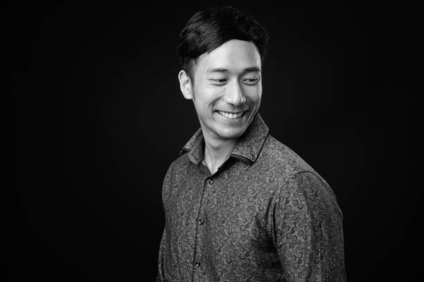 istock Young handsome Asian businessman against black background 1319988147