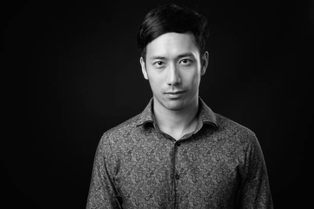 istock Young handsome Asian businessman against black background 1319988155