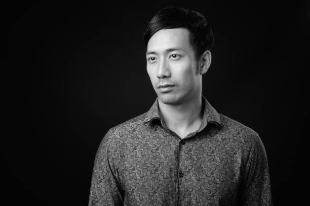 istock Young handsome Asian businessman against black background 1319988184