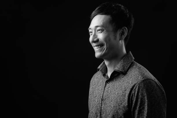 istock Young handsome Asian businessman against black background 1319988194