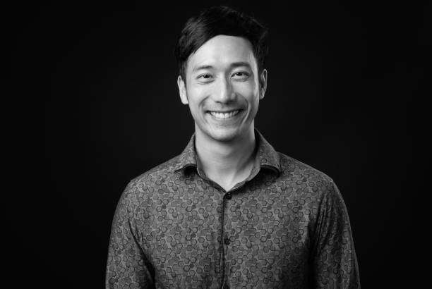 istock Young handsome Asian businessman against black background 1319988212
