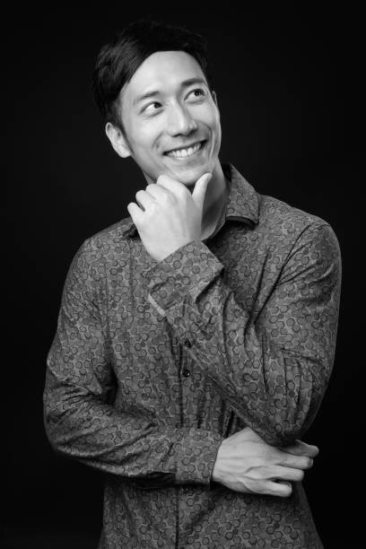 istock Young handsome Asian businessman against black background 1319988231