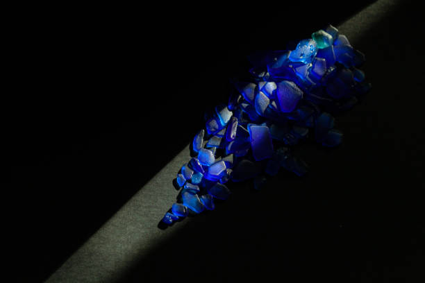 Blue sea glass on black background under sun beam