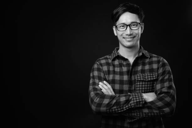 istock Young handsome Asian man against black background 1319988258