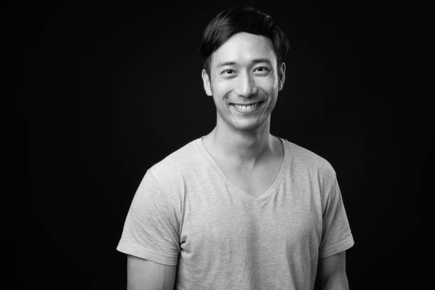 istock Young handsome Asian man against black background 1319988268