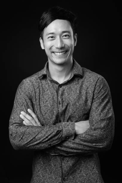 istock Young handsome Asian businessman against black background 1319988321