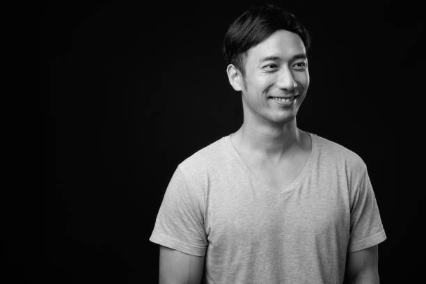 istock Young handsome Asian man against black background 1319988337