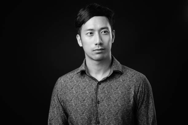 istock Young handsome Asian businessman against black background 1319988375