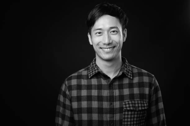 istock Young handsome Asian man against black background 1319988446