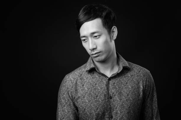 istock Young handsome Asian businessman against black background 1319988470