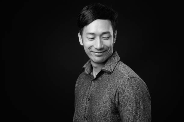 istock Young handsome Asian businessman against black background 1319988508