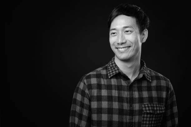 istock Young handsome Asian man against black background 1319988520
