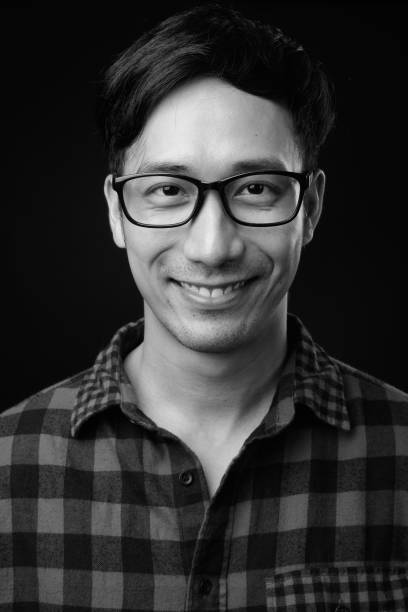 istock Young handsome Asian man against black background 1319988567