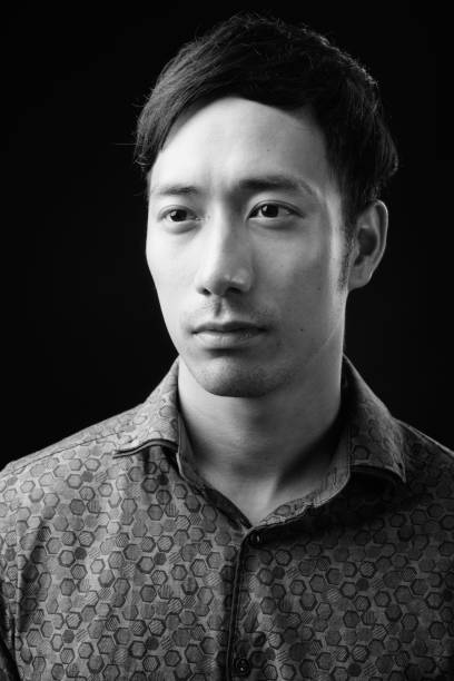 istock Young handsome Asian businessman against black background 1319989119