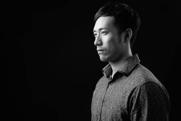 istock Young handsome Asian businessman against black background 1319989148