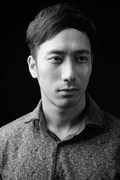 istock Young handsome Asian businessman against black background 1319989177