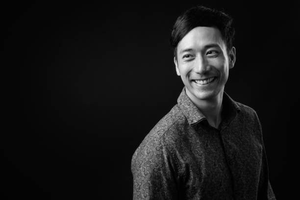 istock Young handsome Asian businessman against black background 1319989708