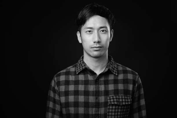 istock Young handsome Asian man against black background 1319989784
