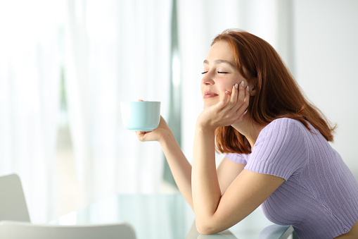 Mujer feliz sosteniendo taza de café descansando en apartamento photo