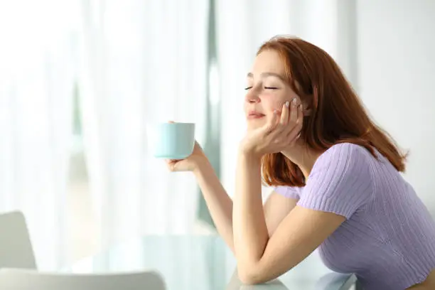 Photo of Happy woman holding coffee cup resting in apartment