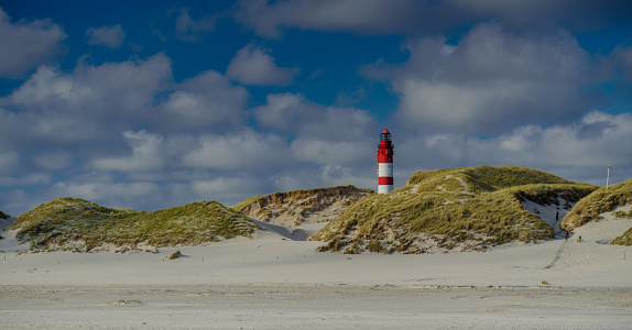 Lighthouse and coastal landscape at North sea on the Isle Amrum, Schleswig-Holstein, Germany. Stunning view from Wadden Sea coastline with lighthouse, wide dunes and sand.