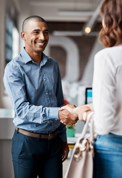 projectile d’un jeune homme d’affaires serrant la main avec une femme dans un bureau - handshake business business person communication photos et images de collection