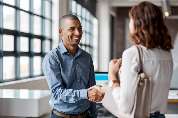 Shot of a young businessman shaking hands with a woman in an office Offering the best service to all their clients casual clothing stock pictures, royalty-free photos & images