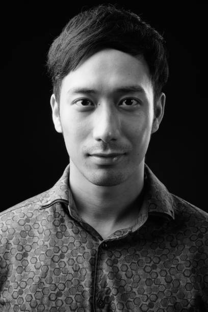 istock Young handsome Asian businessman against black background 1319991649
