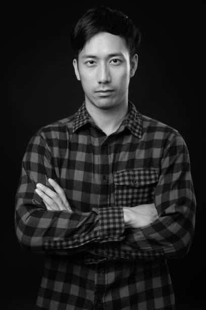 istock Young handsome Asian man against black background 1319991750