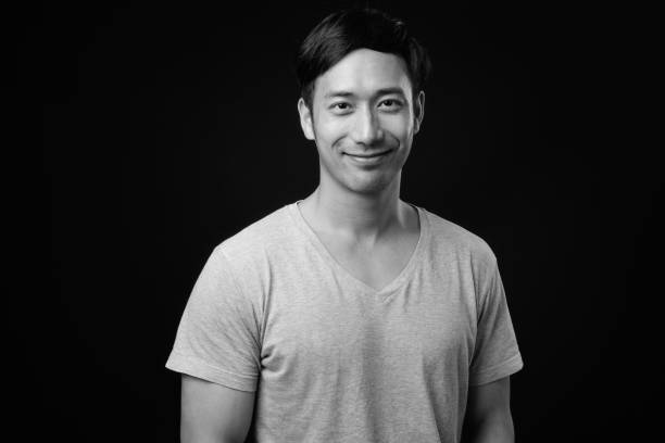 istock Young handsome Asian man against black background 1319991759