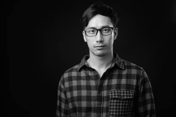 istock Young handsome Asian man against black background 1319991766