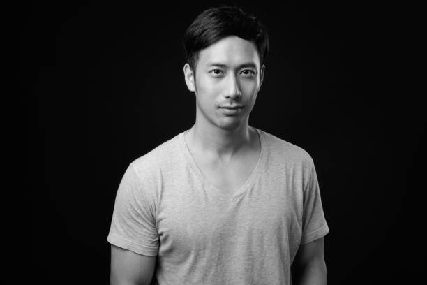 istock Young handsome Asian man against black background 1319991808
