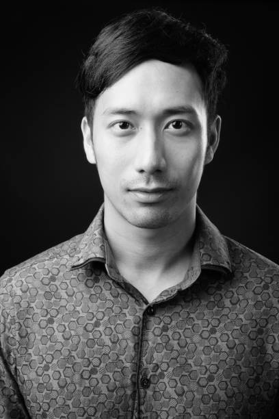 istock Young handsome Asian businessman against black background 1319991820
