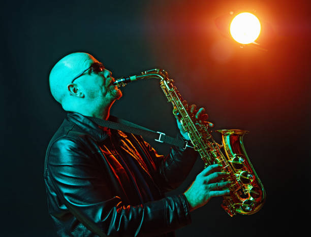 homme jouant un saxophone alto sous un projecteur rouge de scène - light jazz photos et images de collection