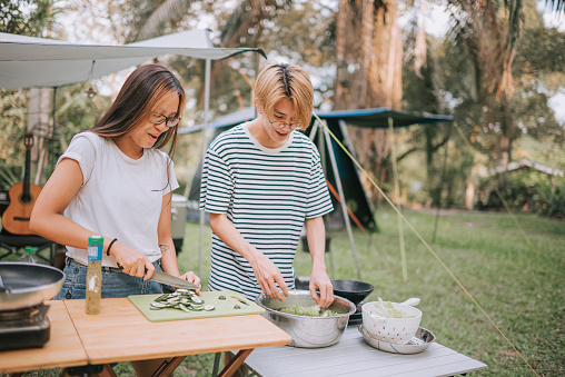 asian chinese sibling teenagers preparing food cooking at camping tent for family, cleaning , soaking and cutting vegetables