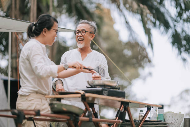 asian chinese senior couple cooking at camping preparing dinner - cooking senior adult healthy lifestyle couple imagens e fotografias de stock