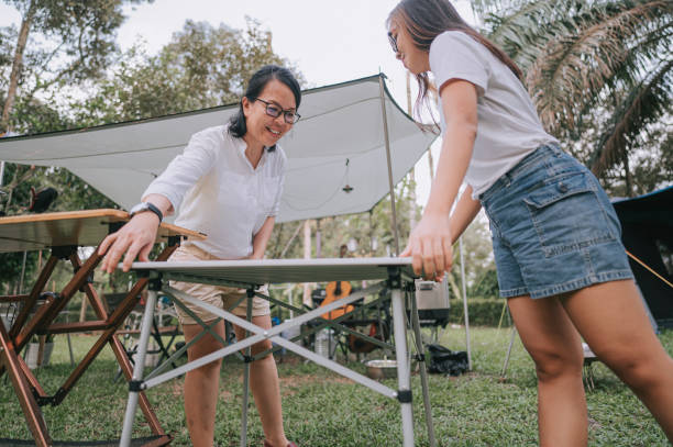 ローアングルビューアジアの中国人の母と娘は、キャンプ場で食べ物の準備のためのピクニックテーブルを設定します - キャンプ　準備 ストックフォトと画像