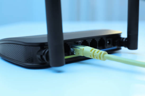 istock Connected cable to router on white table, closeup. Wireless internet communication 1319996381