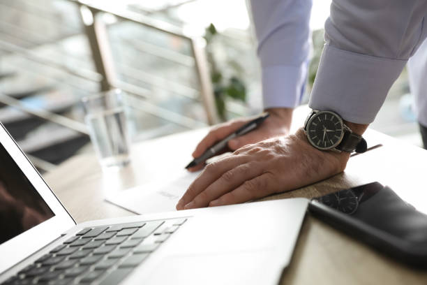 istock Businessman working with documents at wooden desk in office, closeup 1319997446