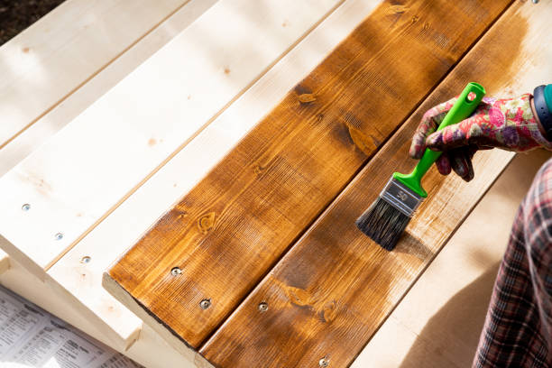 pintura de cubierta de patio de madera con barniz protector. guantes protectores que sostienen pincel pintando superficie de madera, tablones.restaurando muebles de jardín - barnizado de madera fotografías e imágenes de stock