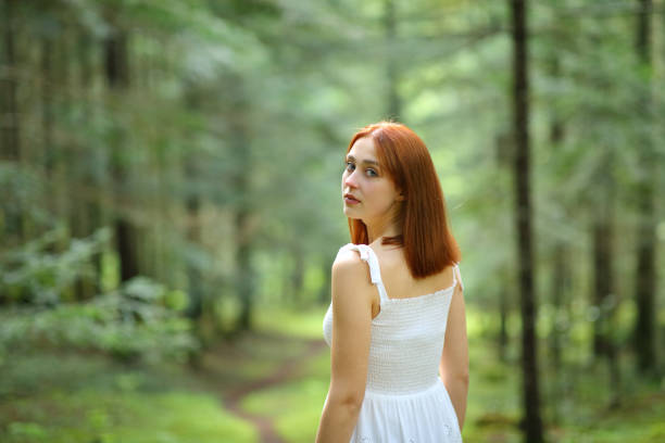 Beautiful woman walking in a forest looking at camera